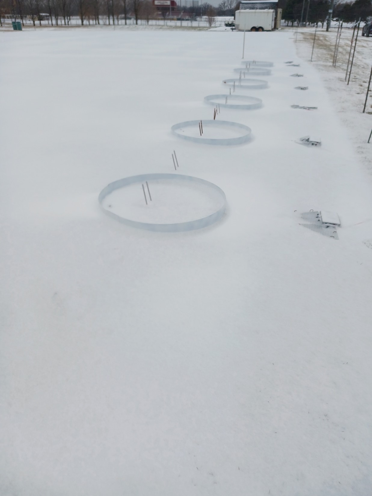 turfgrass research plots with plastic circular structures; snow is covering the landscapes